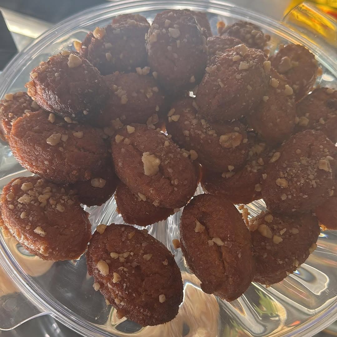 Walnut-topped melomakarona — honey-soaked Greek biscuits in a glass bowl