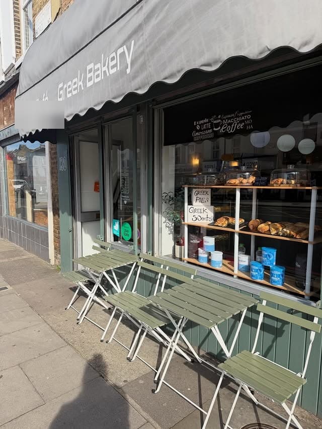 Phyllo & Filo shopfront on Camden Mews — grey scalloped awning reading Greek Bakery, sage bistro chairs and a chalked window listing Greek pies and sweets